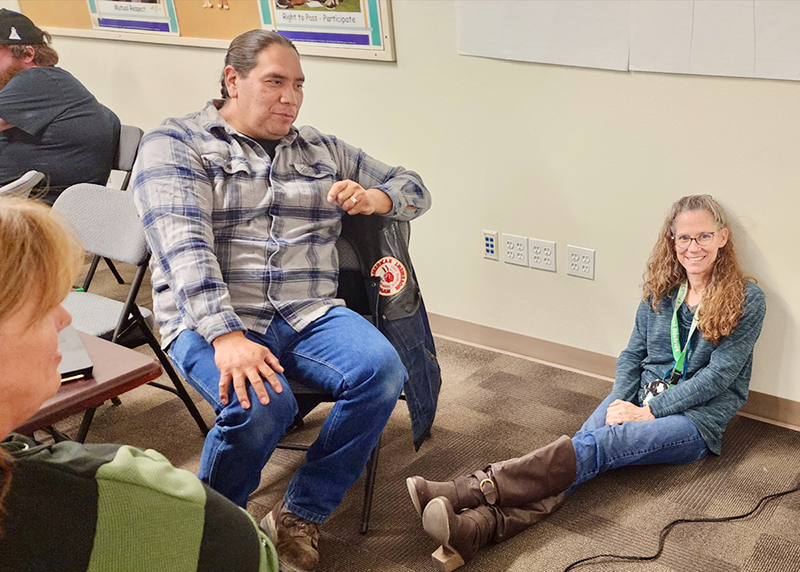 Educators having a discussion at the training. Two in chairs and one sitting on the floor.