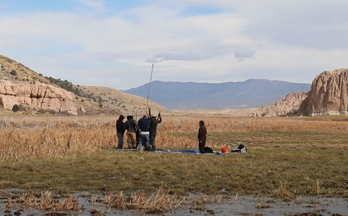 Archaeologists in a meadow collecting a soil core sample. 