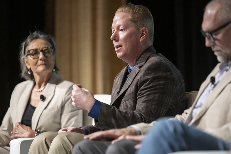 Jesse Murray seated with other panelists on stage at the AWE+ Summit