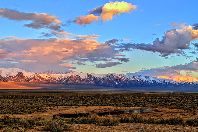 landscape of the desert an sunset with cotton candy clouds and purple mountains in the background. 